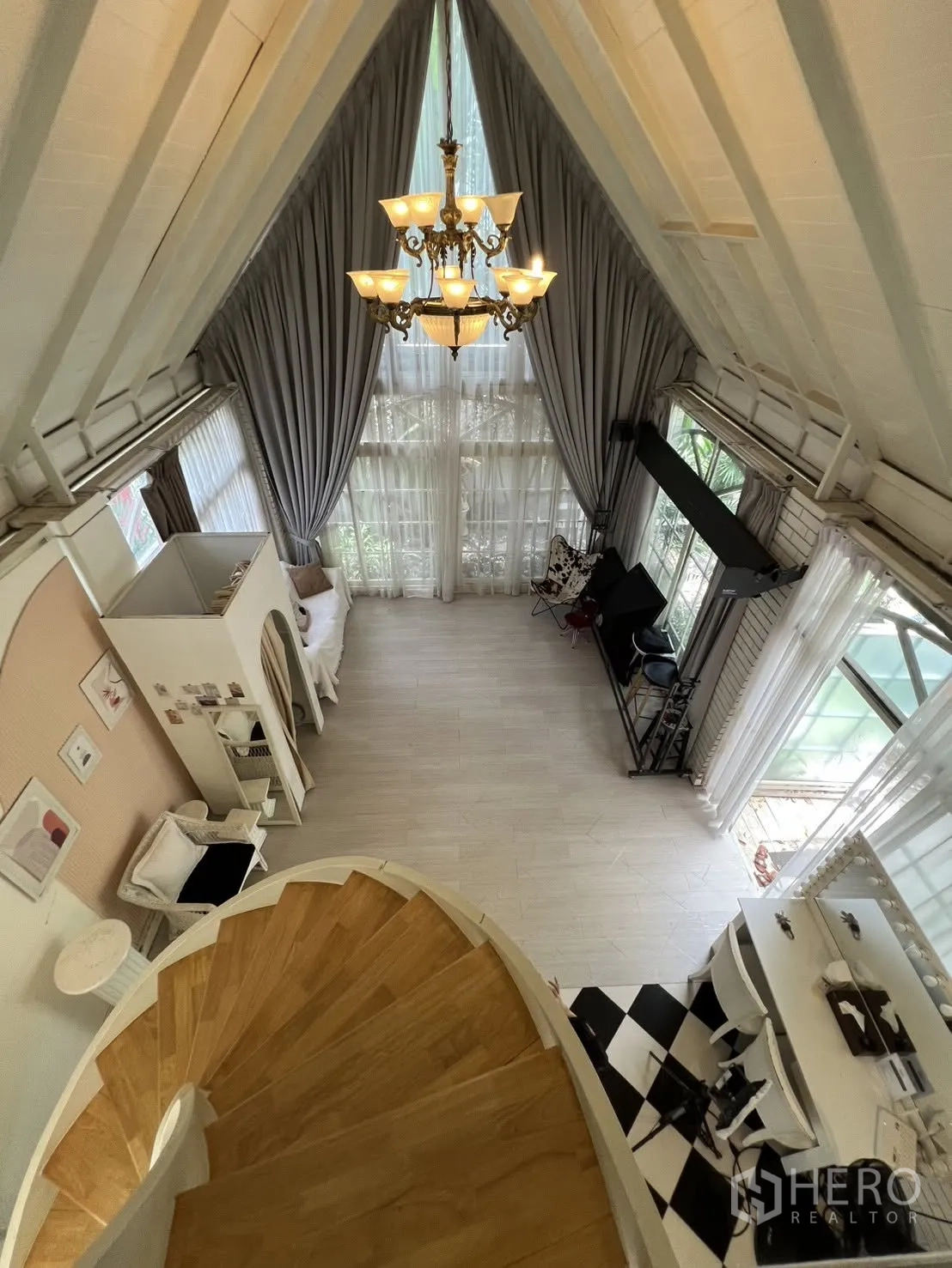 Detached House for rent in Phra Khanong, Bangkok - View from a spiral staircase over a high-ceiling hall with large windows.