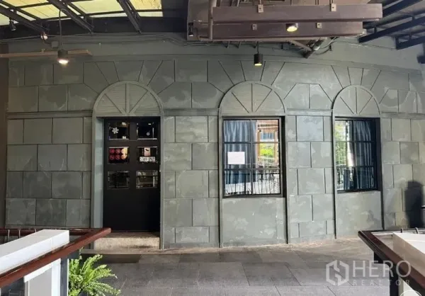 Retail Space for rent - Stone-clad wall with arched windows and an entrance door along an open-air corridor.