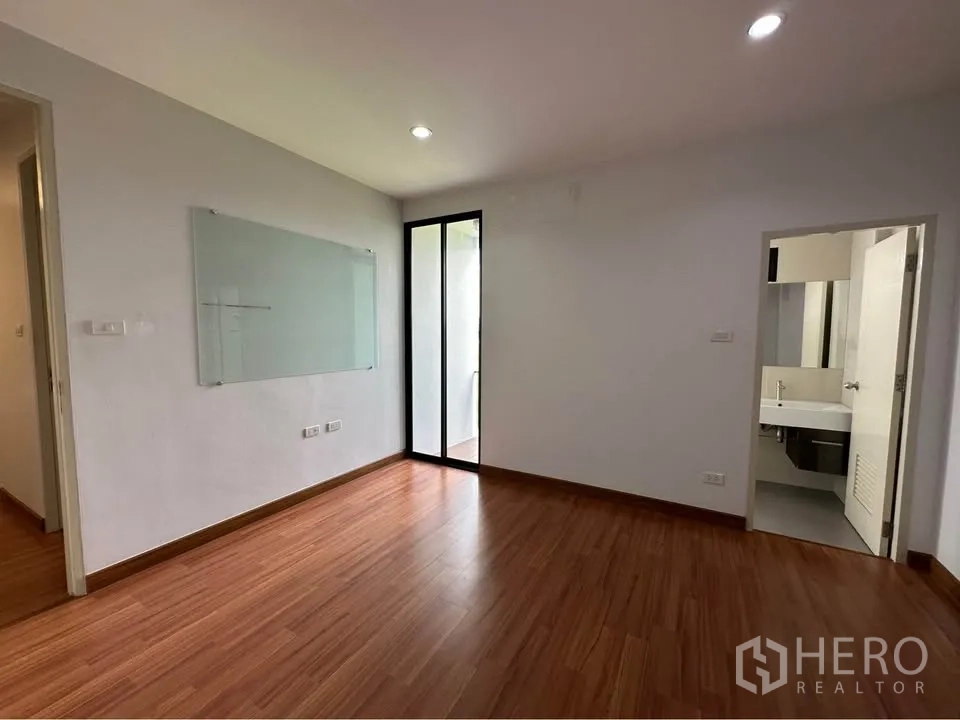联排别墅 出租在Pak Kret, Nonthaburi - 卧室带木地板，玻璃门通往阳台，附套内卫生间门。
