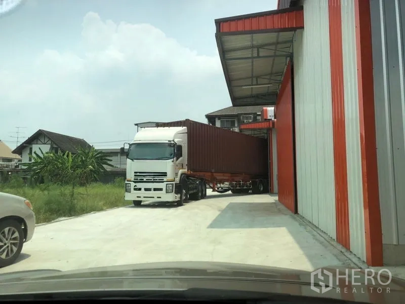 Warehouse for rent in Wang Thonglang, Bangkok - 40-foot container truck maneuvering beside the warehouse under a covered loading bay.