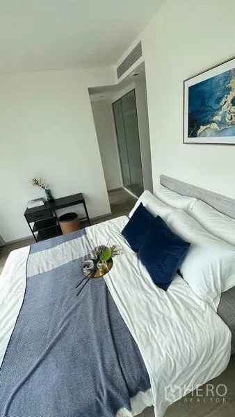 คอนโด ให้เช่าในWatthana, Bangkok - ห้องนอนหลักโทนสีน้ำเงิน–ขาว พร้อมโต๊ะทำงานและตู้เสื้อผ้าบิวท์อินบนพื้นไม้