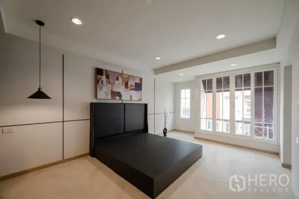 Townhouse for sale - Modern bedroom with large windows, pendant lights and a dark upholstered platform bed.