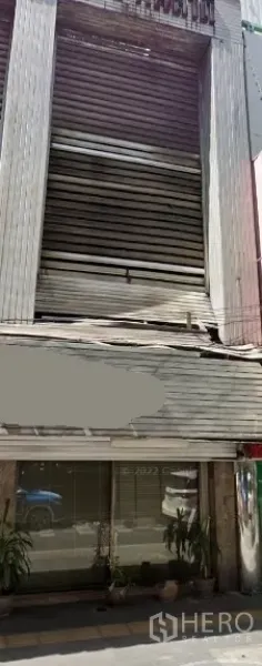 Shophouse for rent in Khlong Toei, Bangkok - Multi-storey shophouse exterior with metal shutters, ground-floor glass shopfront and potted plants near BTS Thonglor in Bangkok.