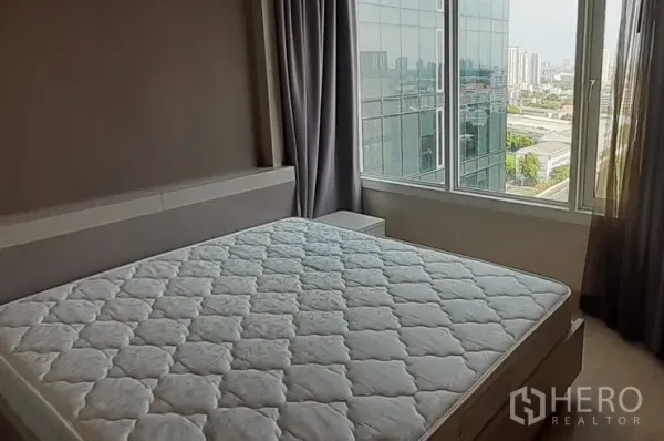 Condominium for rent in Khlong Toei, Bangkok - Bedroom with large window, queen bed and sweeping city skyline views.