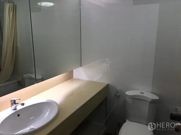 คอนโด ให้เช่าในWatthana, Bangkok - ห้องน้ำโทนขาวมีเคาน์เตอร์ยาว กระจกบานใหญ่ ชักโครก และอ่างอาบน้ำพร้อมผ้าม่าน