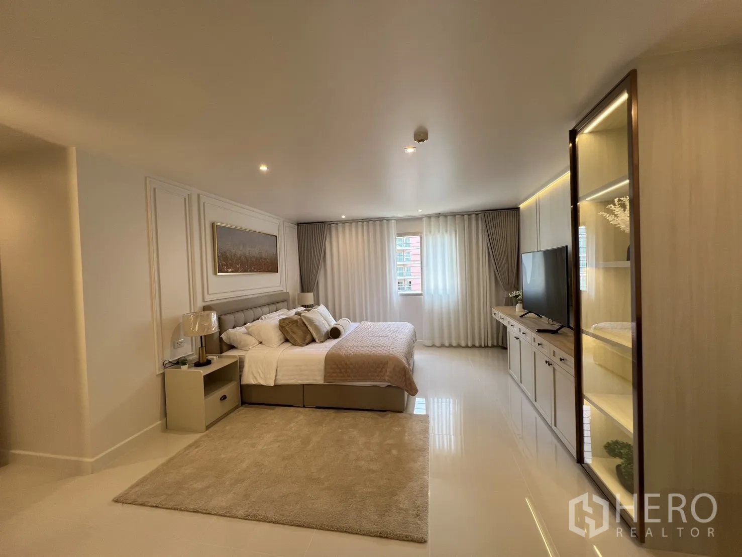Condominium for rent in Yan Nawa, Bangkok - Spacious master bedroom with king bed, rug, and TV cabinet along the wall.