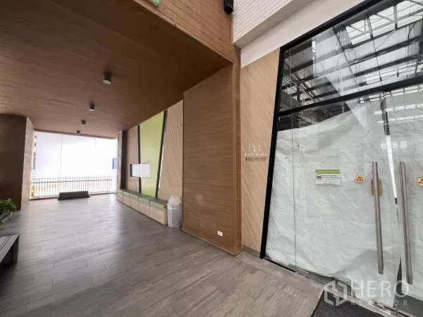 Retail Space for rent in Khlong Toei, Bangkok - Covered common area outside the shop with wood paneling, bench seating, tile flooring and glass entrance.