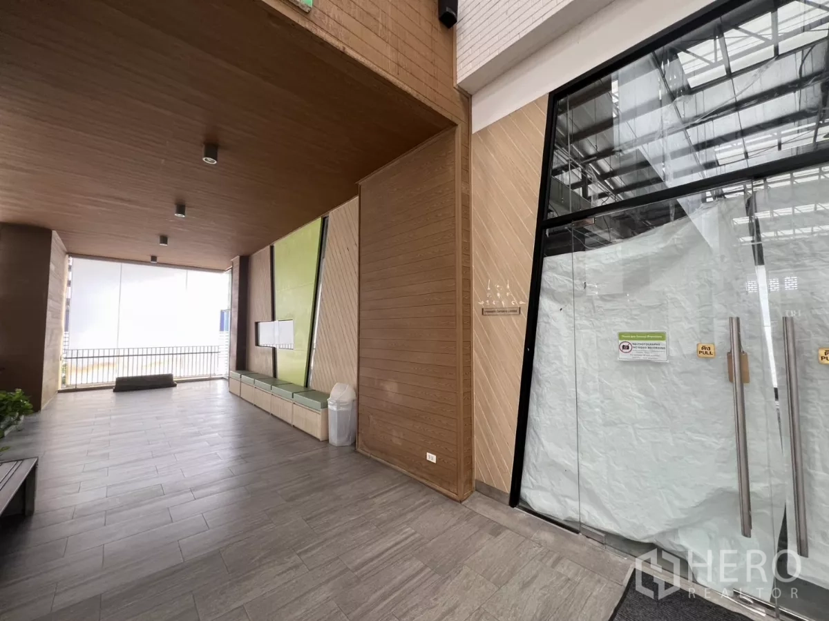 Retail Space for rent in Khlong Toei, Bangkok - Covered common area outside the shop with wood paneling, bench seating, tile flooring and glass entrance.