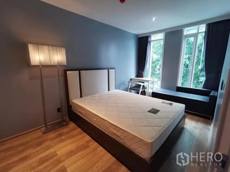 Condominium for rent in Sathon, Bangkok - Second bedroom with big windows, sofa bench and study desk overlooking greenery.