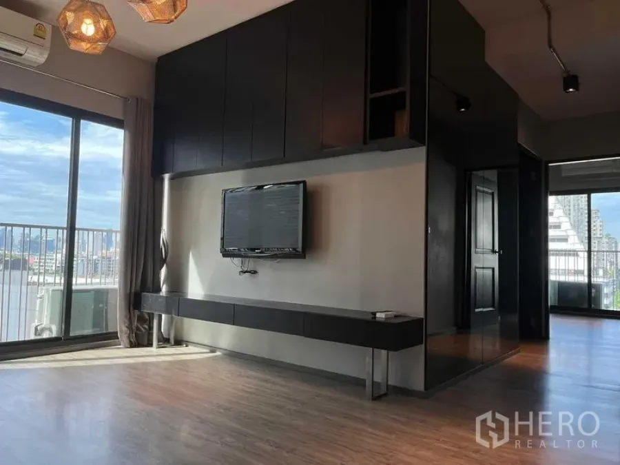 Condominium for sale in Phaya Thai, Bangkok - Bright living room with built-in TV wall, large windows, and balcony city view in Phaya Thai.