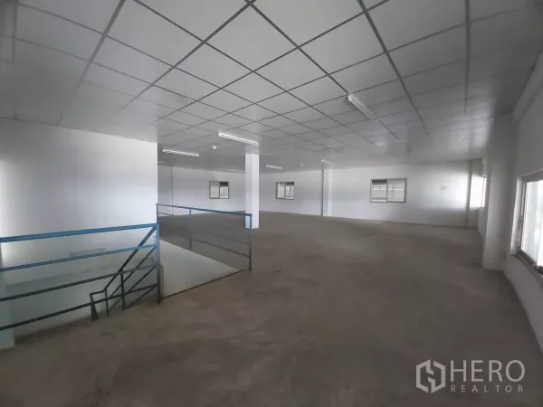 Warehouse for rent in Bang Bo, Samut Prakan - Office mezzanine showing stairwell and wide windows overlooking the warehouse.