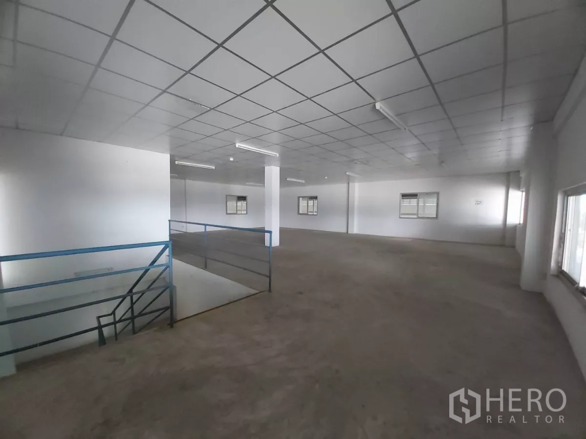 Warehouse for rent in Bang Bo, Samut Prakan - Office mezzanine showing stairwell and wide windows overlooking the warehouse.