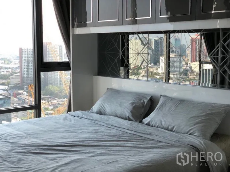Condominium for rent in Khlong Toei, Bangkok - Bedroom featuring glossy cabinetry and mirrored headboard overlooking the city.