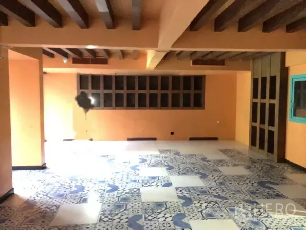 Retail Space for rent in Khlong Toei, Bangkok - Open-plan retail interior with blue-and-white patterned tiles, warm orange walls, exposed ceiling beams, and a long row of windows.