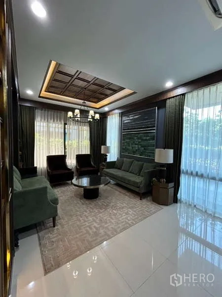 Detached House for rent in Bang Kapi, Bangkok - Elegant living room with coffered ceiling, chandelier, large windows, and plush seating.