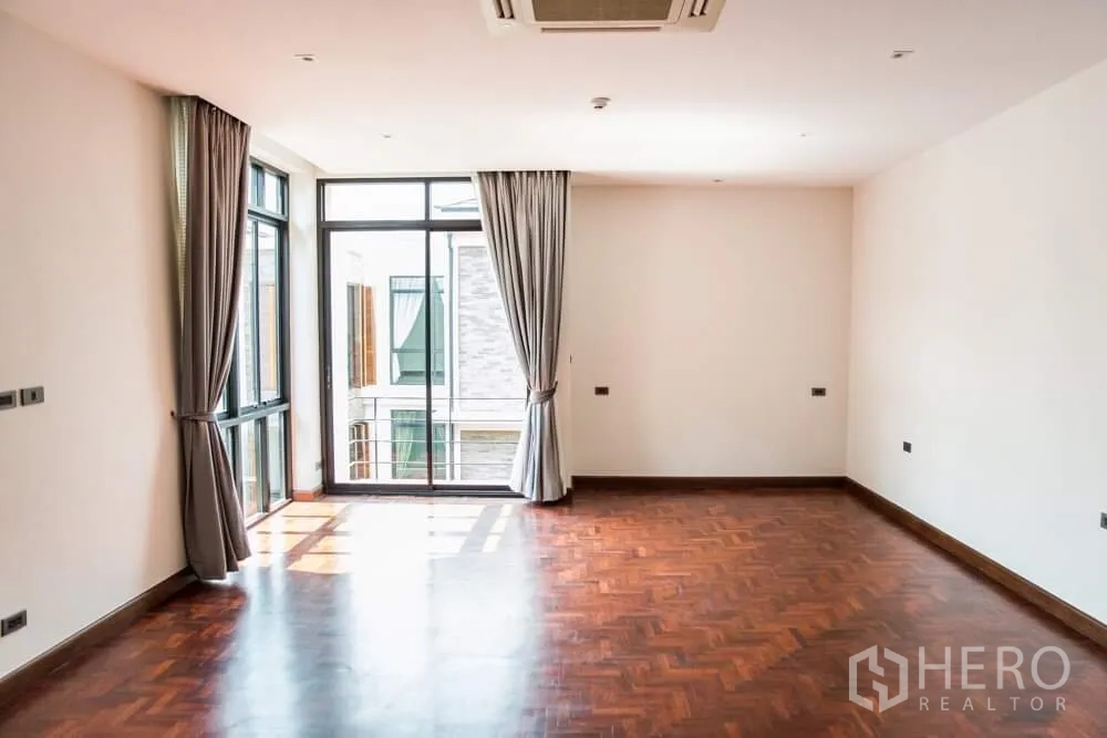 Detached House for rent in Khlong Toei, Bangkok - Spacious bedroom with parquet floor, gray curtains and ceiling cassette air conditioner.