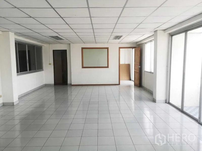 Factory for sale in Khlong Luang, Pathum Thani - Bright tiled office room with drop ceiling, large windows and sliding glass doors.