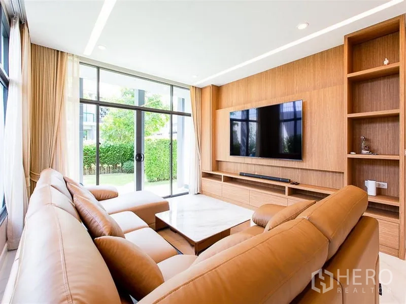 บ้าน ให้เช่าหรือขายในPrawet, Bangkok - ห้องนั่งเล่น โซฟาหนัง ทีวีติดผนัง มองเห็นสวนผ่านประตูกระจก