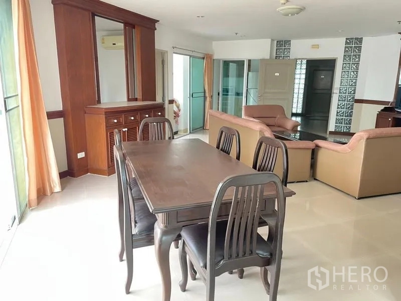 Condominium for rent in Khlong Toei, Bangkok - Dining area with wooden table and chairs beside a built-in storage cabinet.