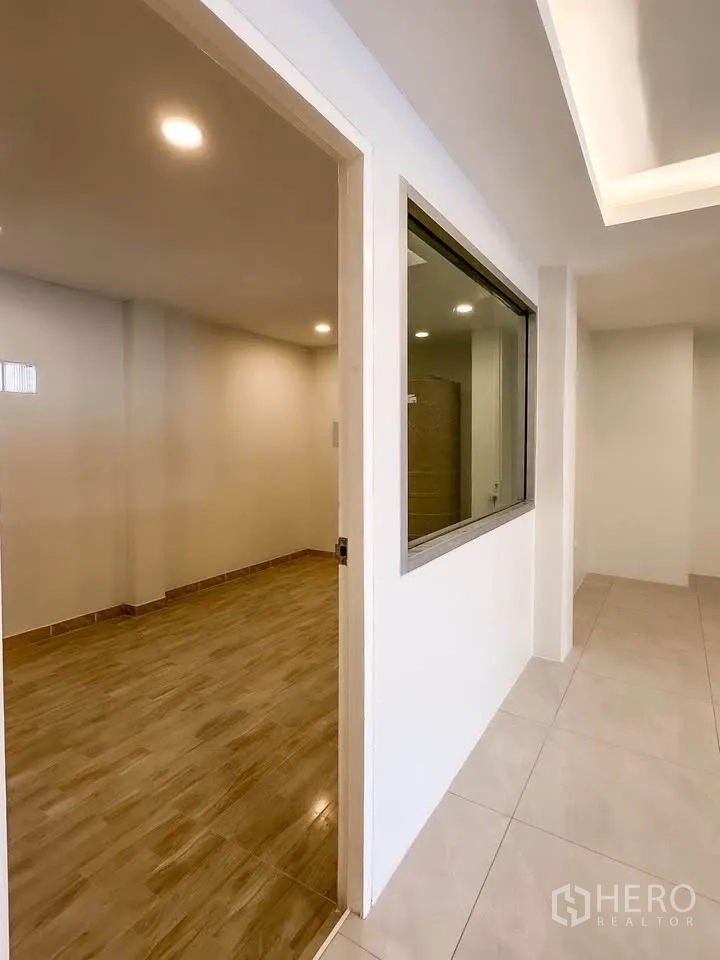 联排别墅 for sale in Wang Thonglang, Bangkok - 走廊带室内窗与通往木纹地房间的门。
