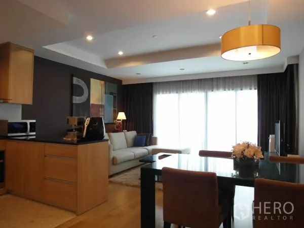 Condominium for rent or sale in Sathon, Bangkok - Open-plan living and dining area with wood floors, large windows and a modern kitchen island in a Sathon condo.