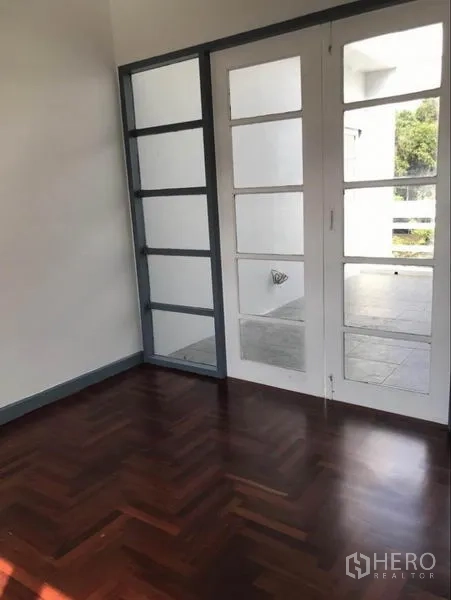 Townhouse for rent in Suan Luang, Bangkok - Bedroom with glass-panel doors opening to a terrace and parquet flooring.