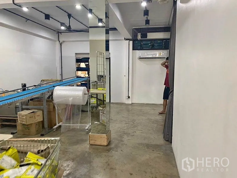 Home Office for rent or sale in Bang Khae, Bangkok - Packing and production room with conveyor table, shelving and exposed ceiling lights.