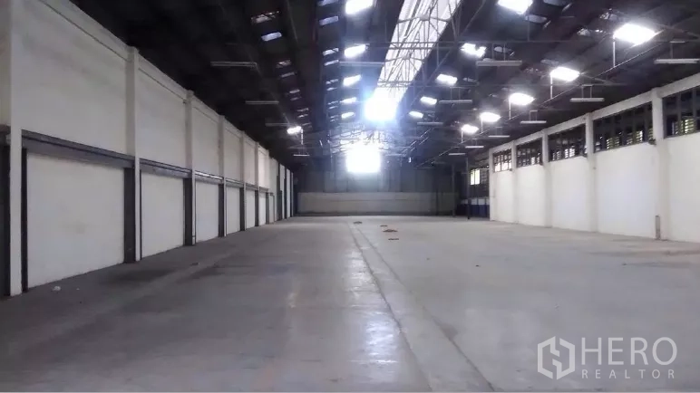 Warehouse for rent in Khlong Luang, Pathum Thani - Clear-span shed with central skylight and side ventilation fans for airflow.