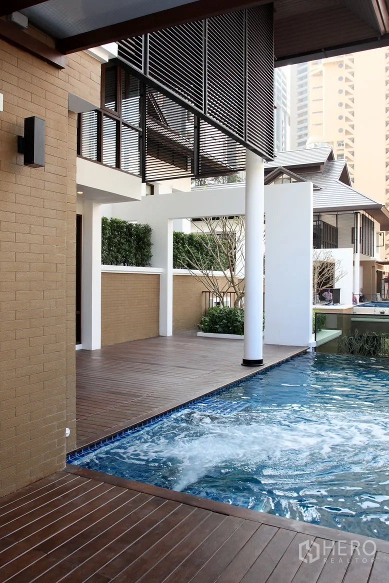Detached House for rent in Khlong Toei, Bangkok - Covered terrace with wooden deck next to a bubbling swimming pool and modern louvered sunshades.