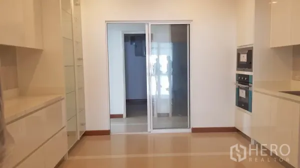 公寓 出租或出售在Yan Nawa, Bangkok - 带长操作台的厨房，玻璃推拉门通往家务区。