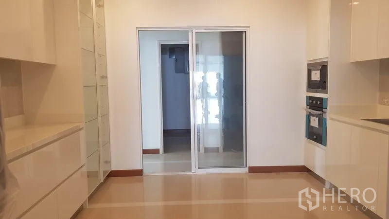 公寓 出租或出售在Yan Nawa, Bangkok - 带长操作台的厨房，玻璃推拉门通往家务区。