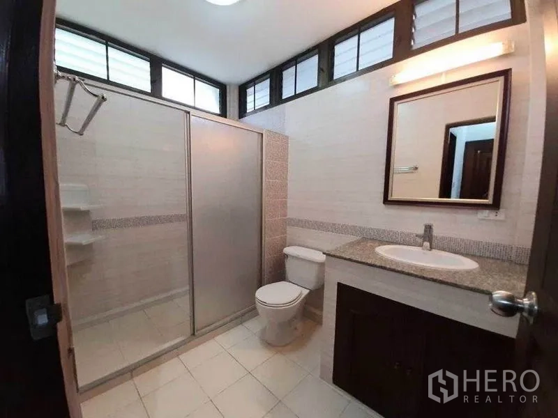 Detached House for rent in Watthana, Bangkok - Bathroom with glass shower enclosure, vanity countertop and upper ventilated windows.