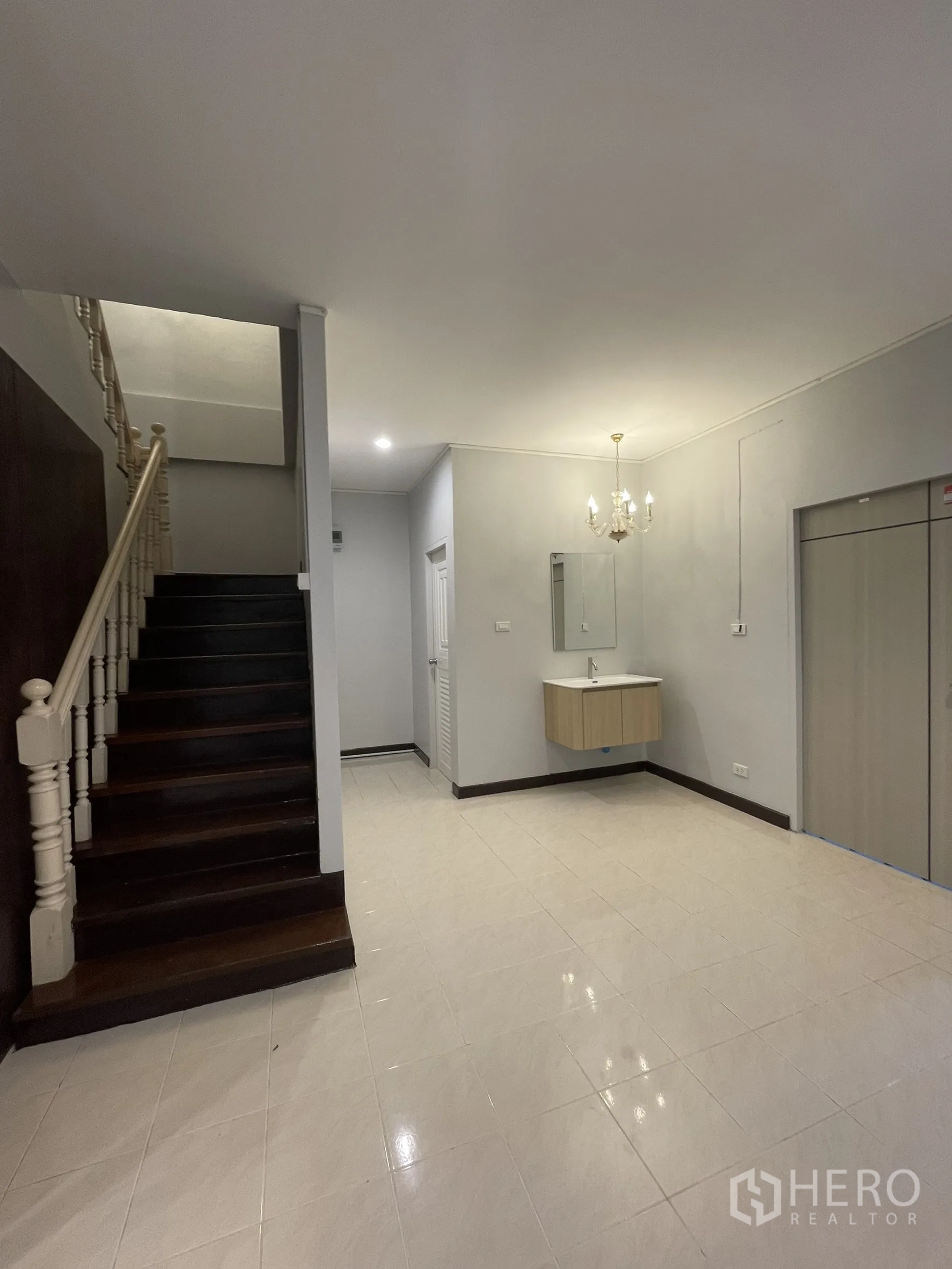 店屋 for rent in Bang Kapi, Bangkok - 一层走廊带楼梯，亮面瓷砖地与墙挂洗手台，顶配枝形吊灯。