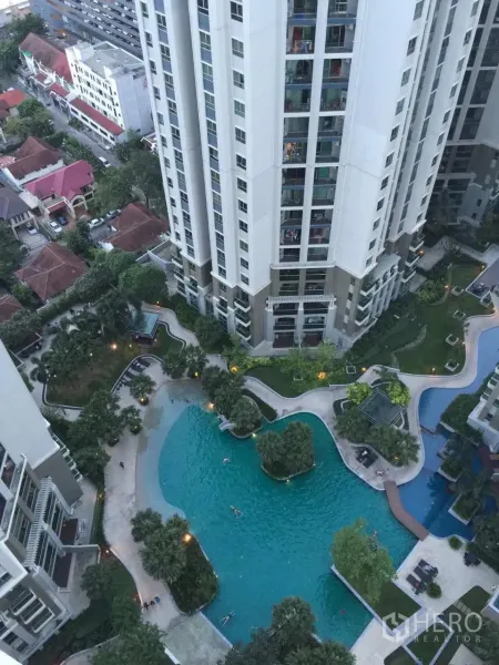 Condominium for rent in Huai Khwang, Bangkok - Aerial view of a high-rise condominium with a resort-style lagoon swimming pool and landscaped gardens in Huai Khwang.