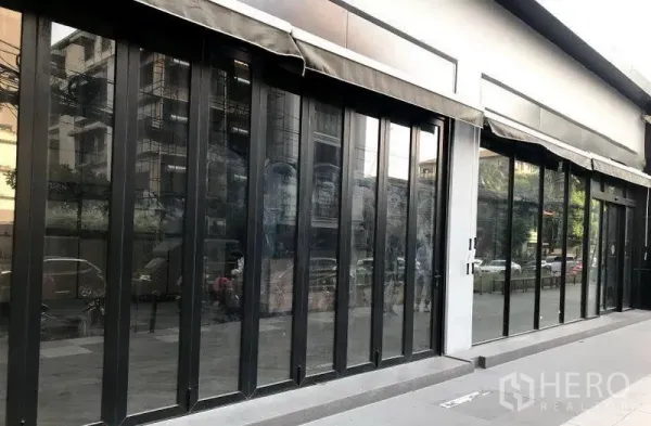 零售空间 出租在Khlong Toei, Bangkok - 黑色框架的推拉玻璃店面近景，带遮阳棚，临街视野，Thonglor区域。
