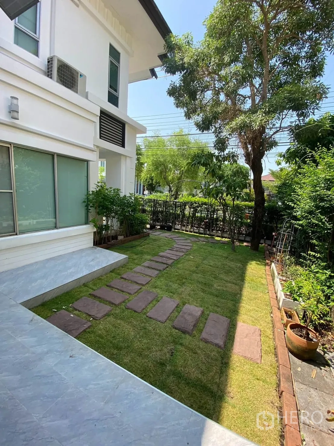 独栋房屋 for rent in Mueang Samut Prakan, Samut Prakan - 白色外墙旁的草坪花园，设踏步石小径。