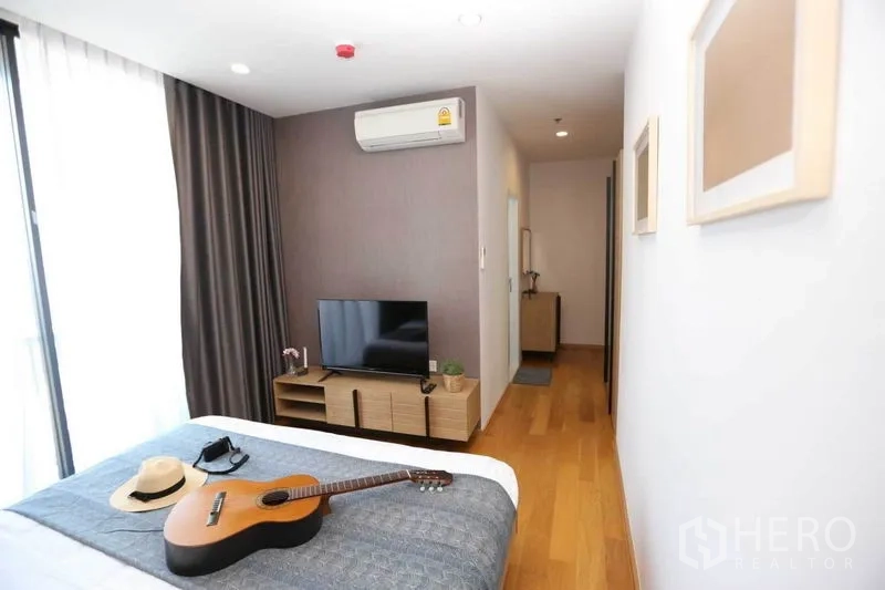 公寓 出租或出售在Bang Rak, Bangkok - 卧室朝走廊视角，电视柜与遮光窗帘大窗
