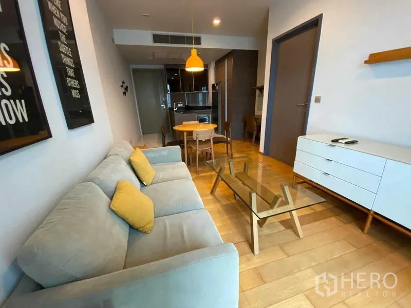 公寓 出租在Khlong Toei, Bangkok - 从客厅望向厨房的空间：沙发、餐桌组与吊灯。
