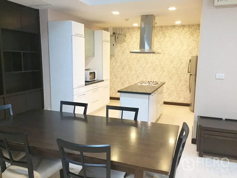 Condominium for rent in Khlong Toei, Bangkok - Modern white kitchen with island cooktop and ample cabinetry.