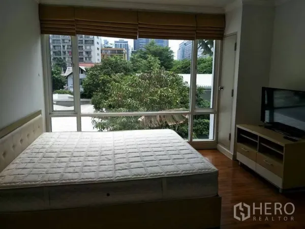 公寓 出租在Khlong Toei, Bangkok - 卧室配大床，落地窗带城市与树梢景观，百叶窗与电视柜一应俱全