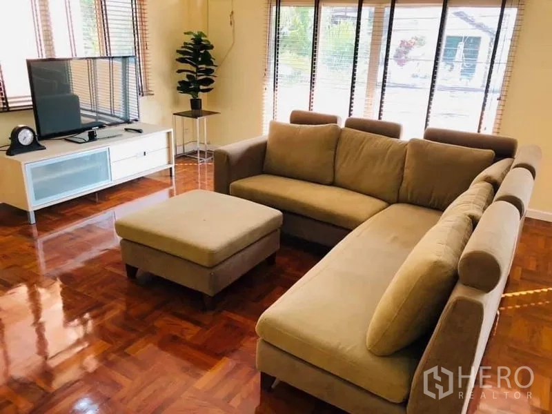 Detached House for rent in Watthana, Bangkok - Second family lounge with a beige sectional sofa, ottoman, TV console, and parquet floors.