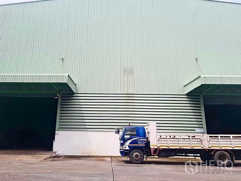 คลังสินค้า ให้เช่าในPhra Pradaeng, Samut Prakan - ช่องโหลดสินค้าของโกดังมีรถบรรทุกจอดบนลานคอนกรีต