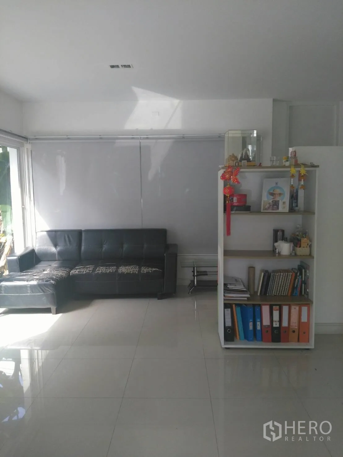 公寓 出租在Pathum Wan, Bangkok - 明亮客厅，亮面瓷砖地板，黑色转角沙发与白色置物架，大窗采光