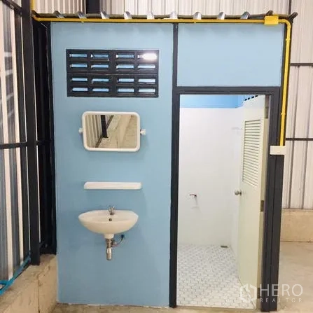 Warehouse for rent in Khan Na Yao, Bangkok - On-site restroom with sink, mirror, and tiled shower area inside the warehouse.