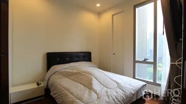 Condominium for rent in Khlong Toei, Bangkok - Cozy bedroom with double bed, bedside table and floor-to-ceiling window with city view.