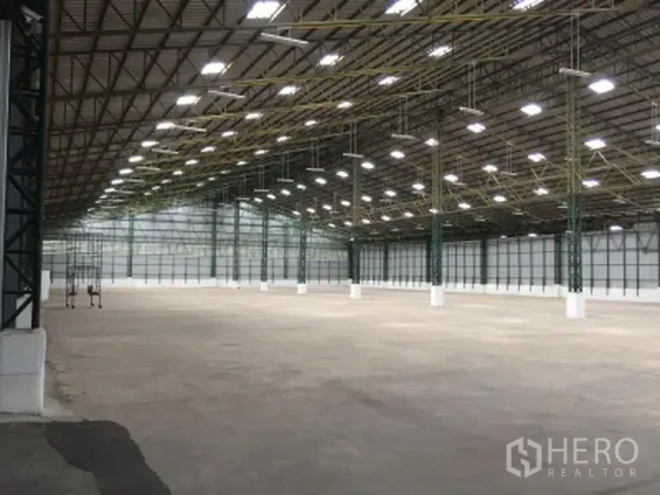 Warehouse for rent in Mueang Pathum Thani, Pathum Thani - Expansive warehouse interior with high steel-truss roof, bright LED lighting and smooth concrete floor.