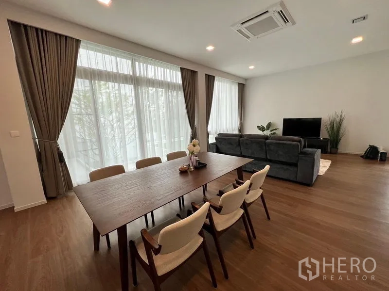 Detached House for rent - Open-plan living and dining area with floor-to-ceiling windows, wood floors and a grey sofa.