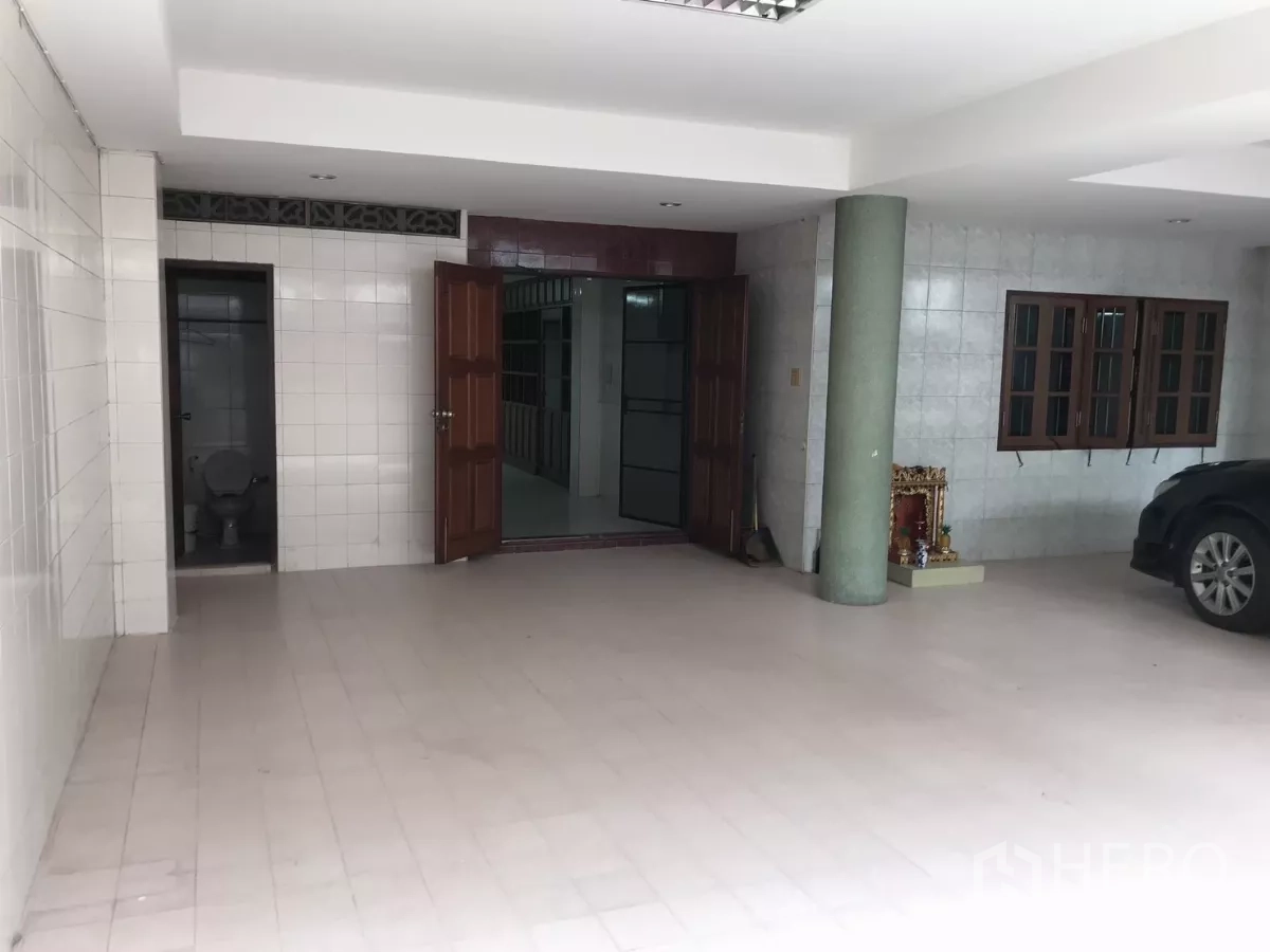 Home Office for rent in Dusit, Bangkok - Covered ground-floor carport with tiled surfaces, restroom, and wide entrance doors.