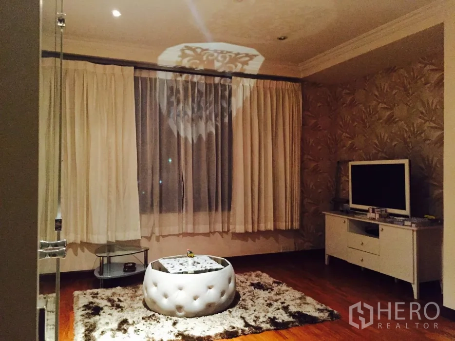 Condominium for rent in Sathon, Bangkok - Warm living room with TV console, round tufted ottoman and shag rug under recessed lights.