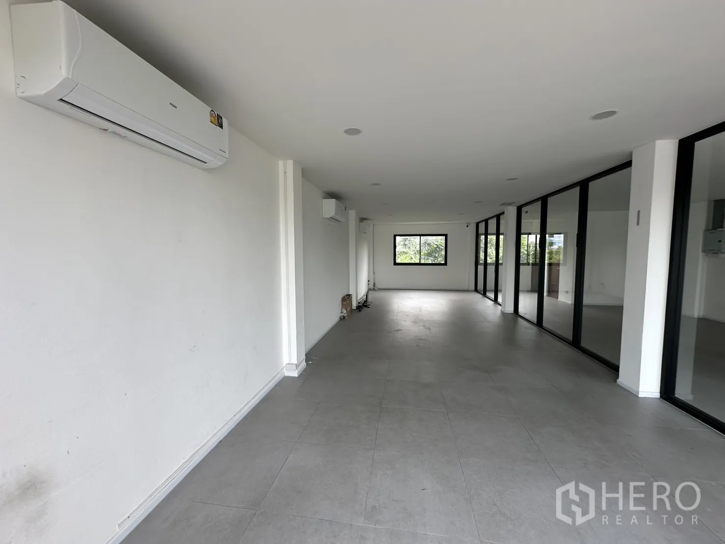Home Office for rent or sale in Bang Na, Bangkok - White-walled office zone with air conditioners and a glass wall.